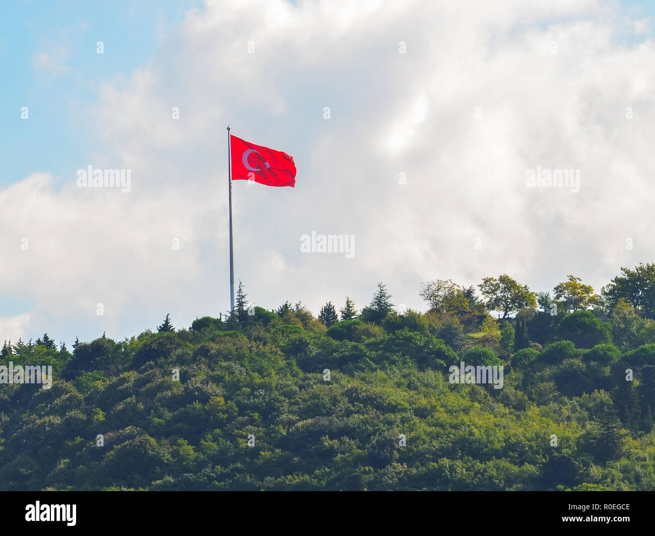 Türkische Flagge auf einer grünen, bewaldeten Hügel, auf dem Hintergrund der Wolken und blauer Himmel clouse. Stockfoto