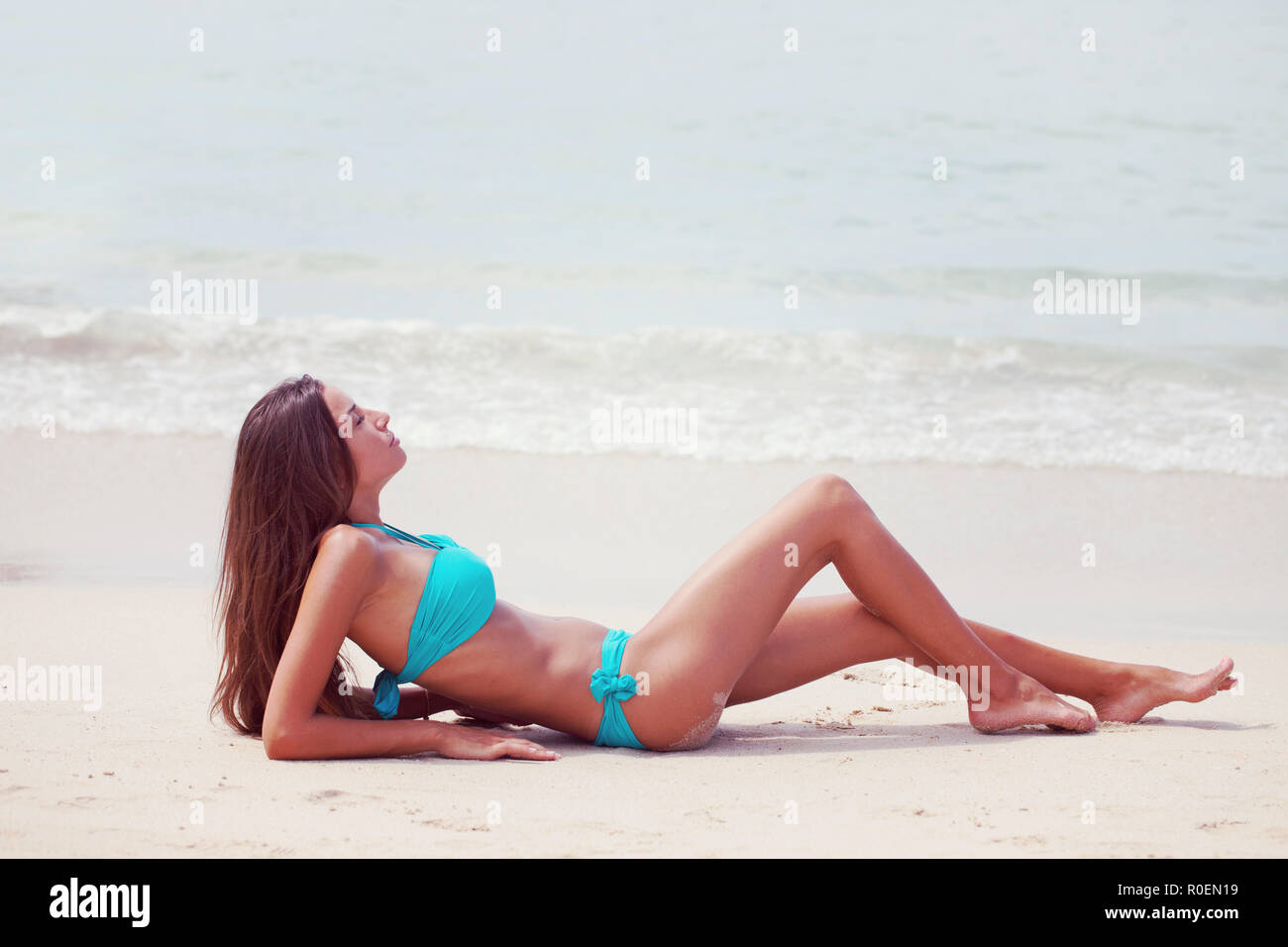 Frau in großen Hut sitzt am Strand am Meer Stockfoto