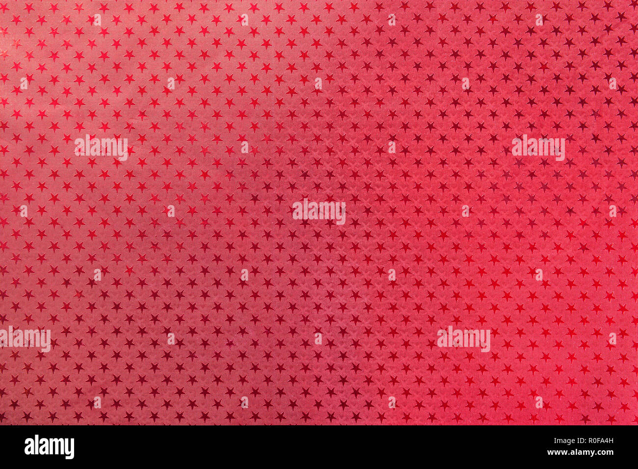 Roter Hintergrund aus Metallfolie Papier mit einem Muster der funkelnden Sterne Nahaufnahme. Textur von metallisierten Verpackung urlaub Papier Oberfläche. Stockfoto