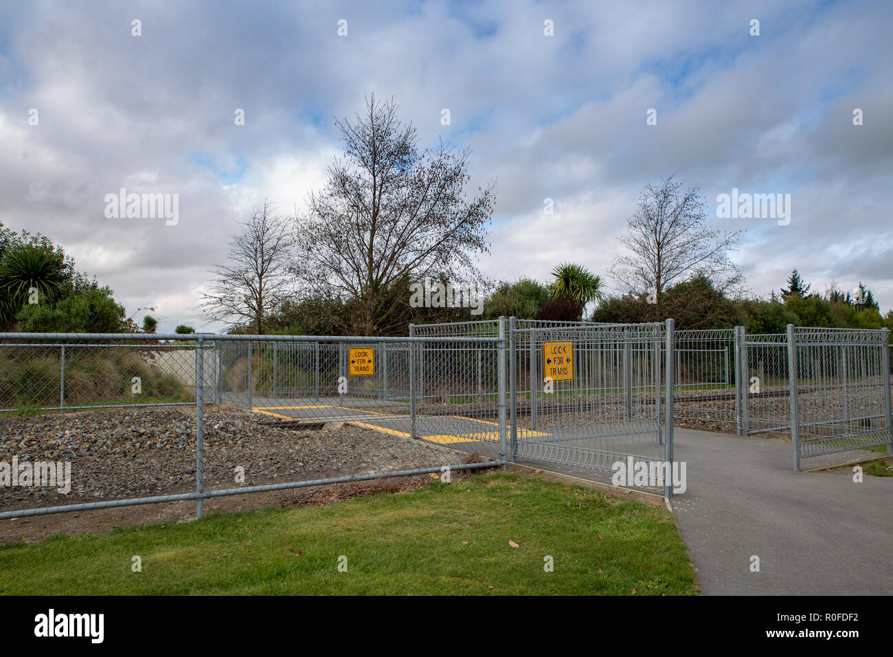 Zaun Barrieren und gelbe Schilder sind eine Vorsicht zu Überqueren der Bahnlinie entlang einer öffentlichen Weg Stockfoto