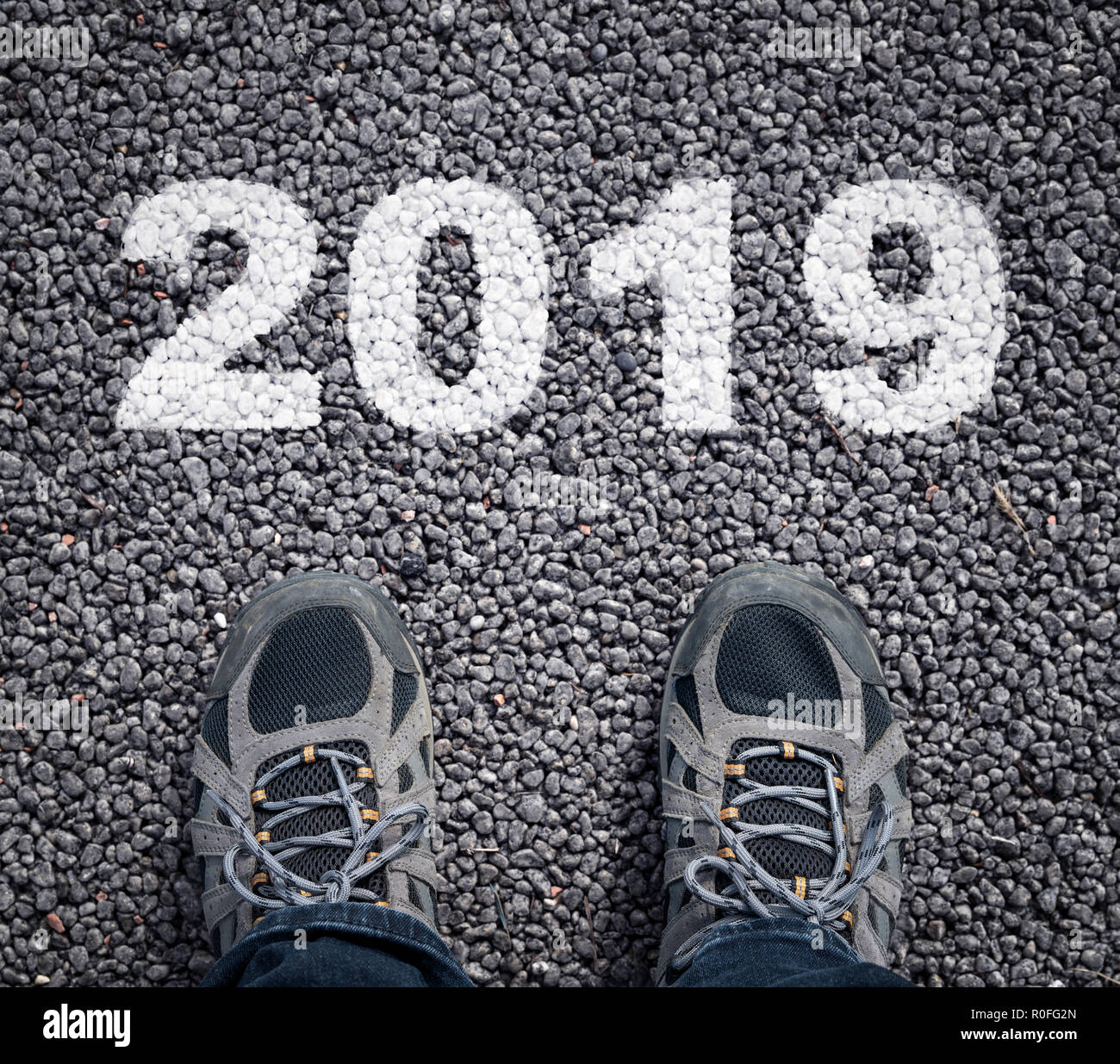 Frohes neues Jahr 2019. Mann Beine in Turnschuhen auf der asphaltierten Straße und Nummer 2019. Stockfoto