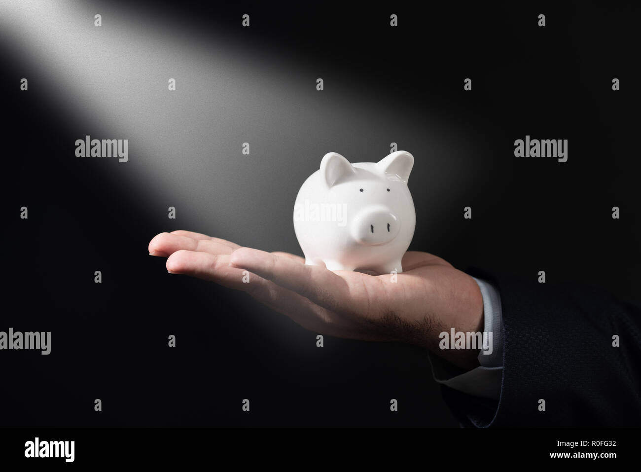 Geschäftsmann in Anzug hält Sparschwein. Finanzierung Einsparungen Konzept. Stockfoto