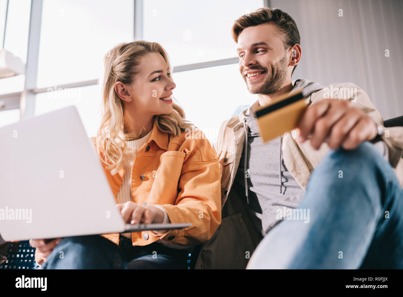 Lächelnder Mann mit Kreditkarte und junge Frau mit Laptop im Flughafen Stockfoto