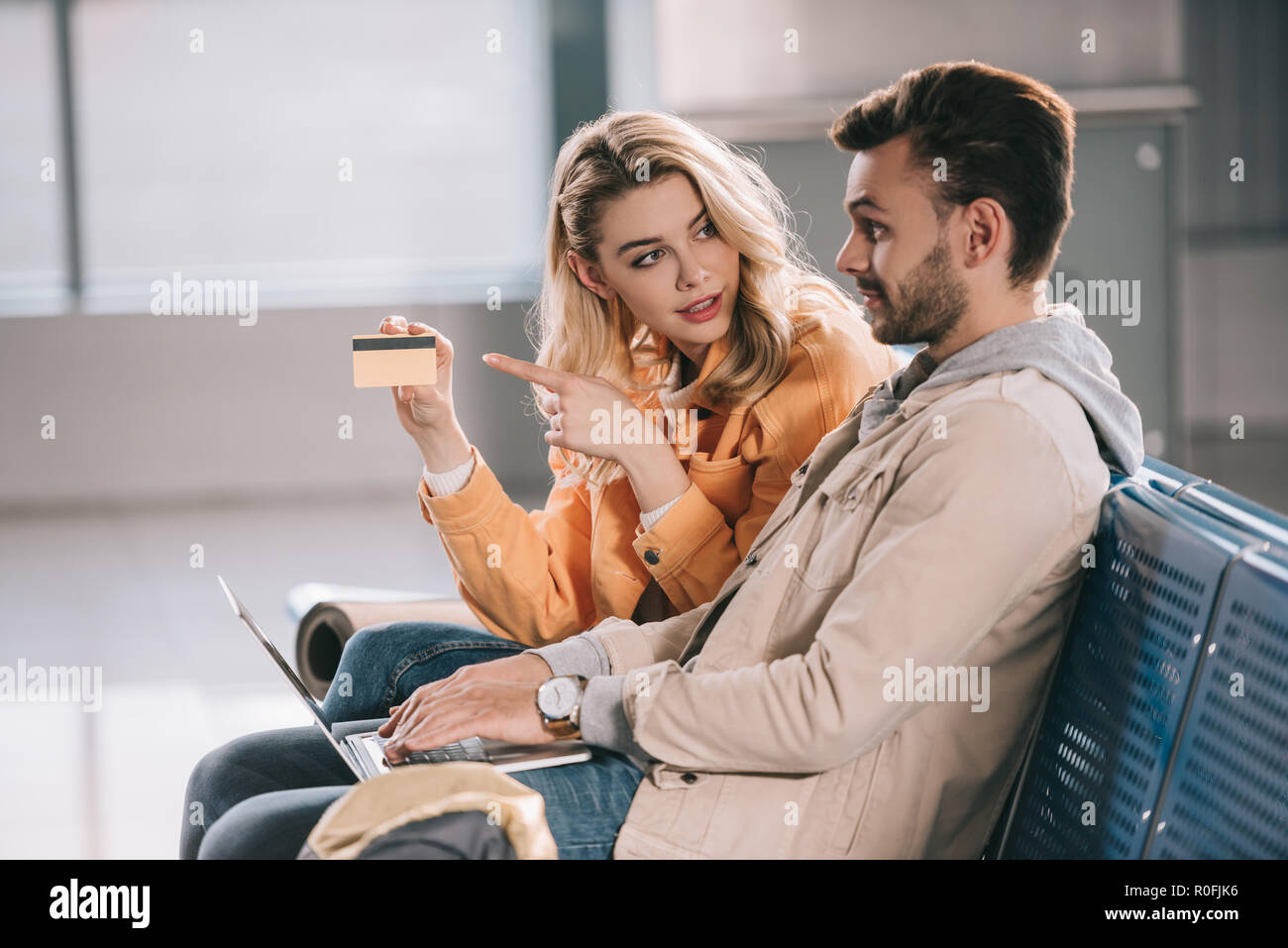 Mädchen zeigte mit dem Finger auf Kreditkarte und Mann mit Laptop im Flughafen Stockfoto