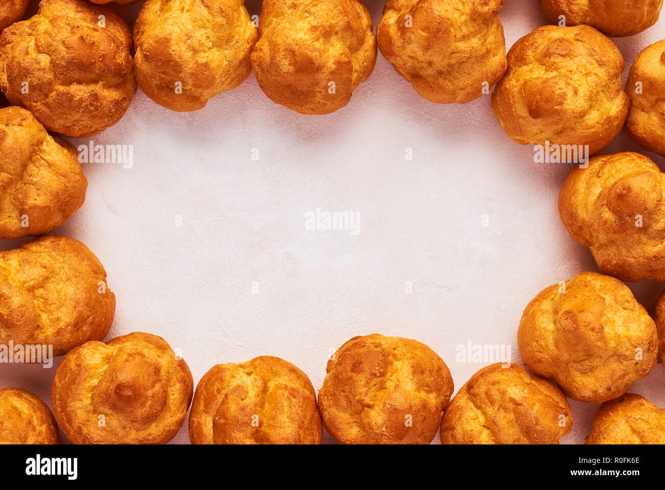 Rahmen aus frischer Sahne puste Kuchen auf rose Hintergrund mit kopieren. Ansicht von oben. Stockfoto