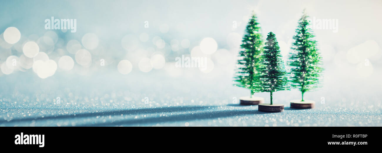 Magische Miniatur Wunderland Banner. Evergreen Weihnachtsbäume auf glänzenden blauen Hintergrund mit Bokeh. Stockfoto