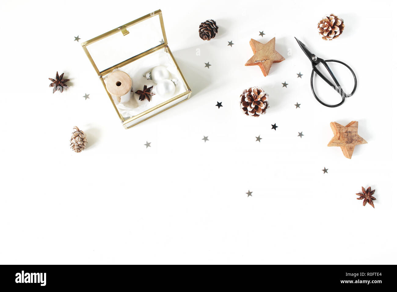 Christmas Craft Komposition. Seidenbändern und Weihnachtskugeln in goldenen Glasbehälter. Vintage Schere, Tannenzapfen, silber Konfetti- und Holz- Sterne. Weißem Hintergrund. Flach, Ansicht von oben Stockfoto