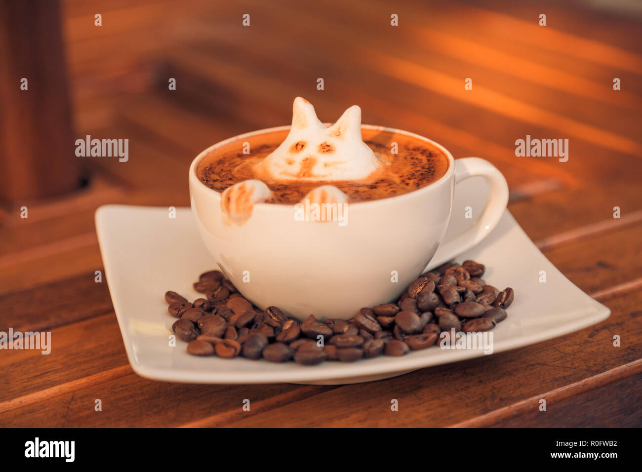 Heiße Kunst latte Kaffee in einer Tasse auf Holztisch und Coffee Shop blur Hintergrund mit bokeh Bild. Latte Art Coffee table top, gerne entspannende Stimmung Stockfoto