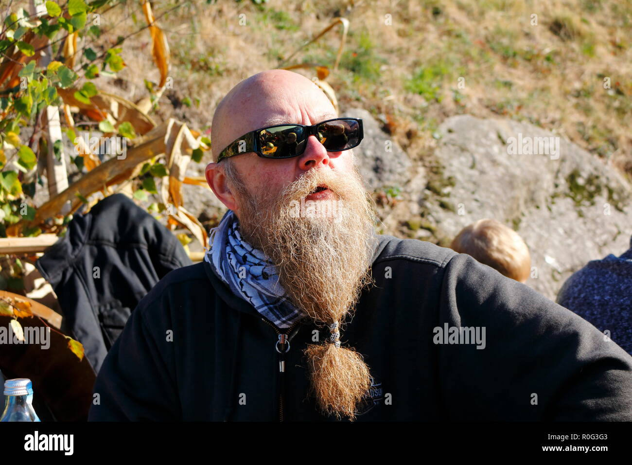 Mann mit langem Bart lächelt und genießt die letzten Sonnenstrahlen im Herbst beim Erntedankfest Stockfoto