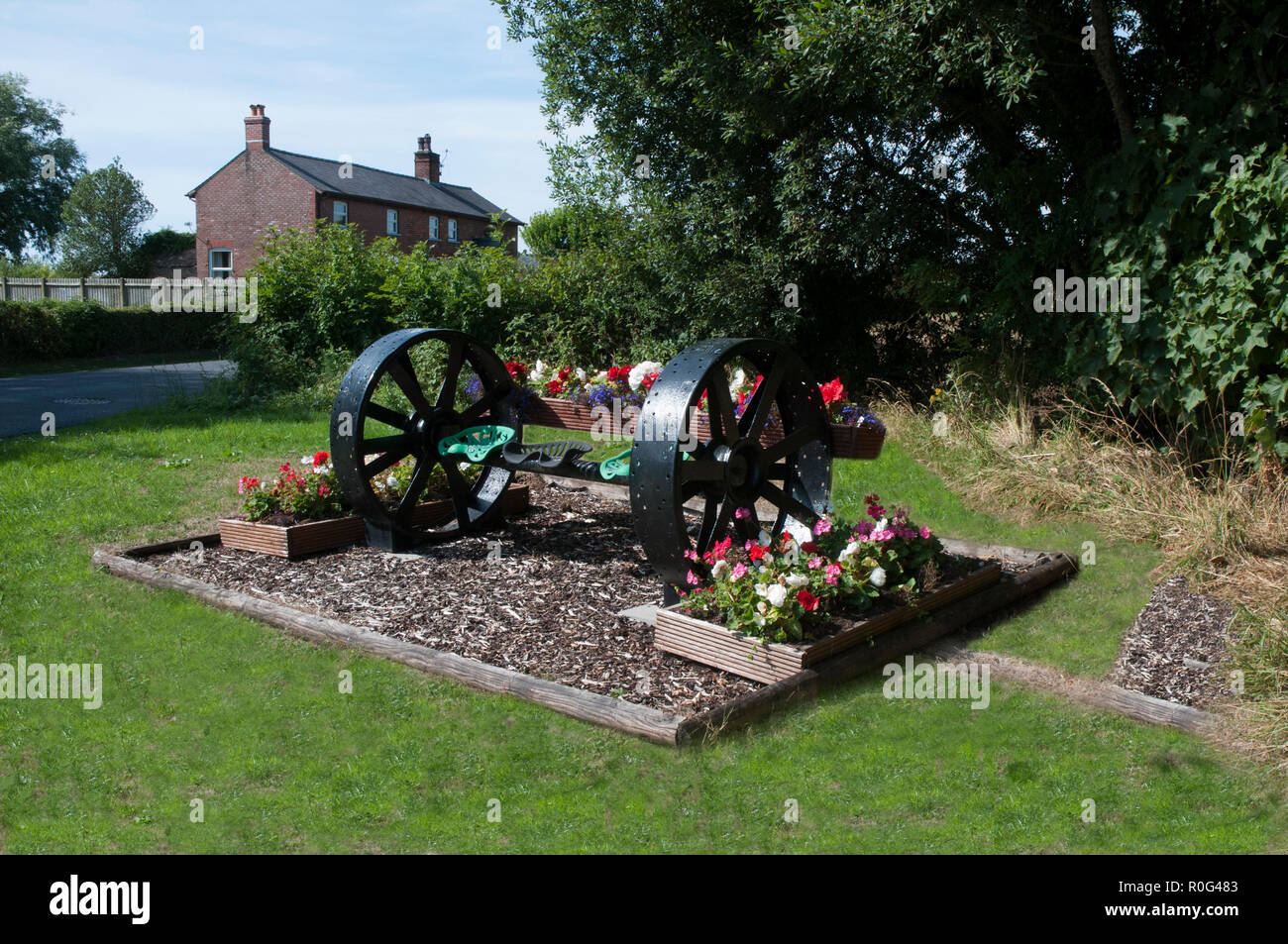 Blume am Straßenrand Anzeige von Begonien und Geranien mit einem landwirtschaftlichen Gerät als Mittelstück. stalmine Dorf BlackpooL Lancashire England Großbritannien Stockfoto