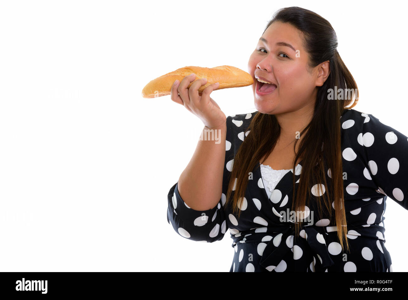 Studio shot von jungen asiatischen Fett glücklich lächelnde Frau beim Essen Stockfoto