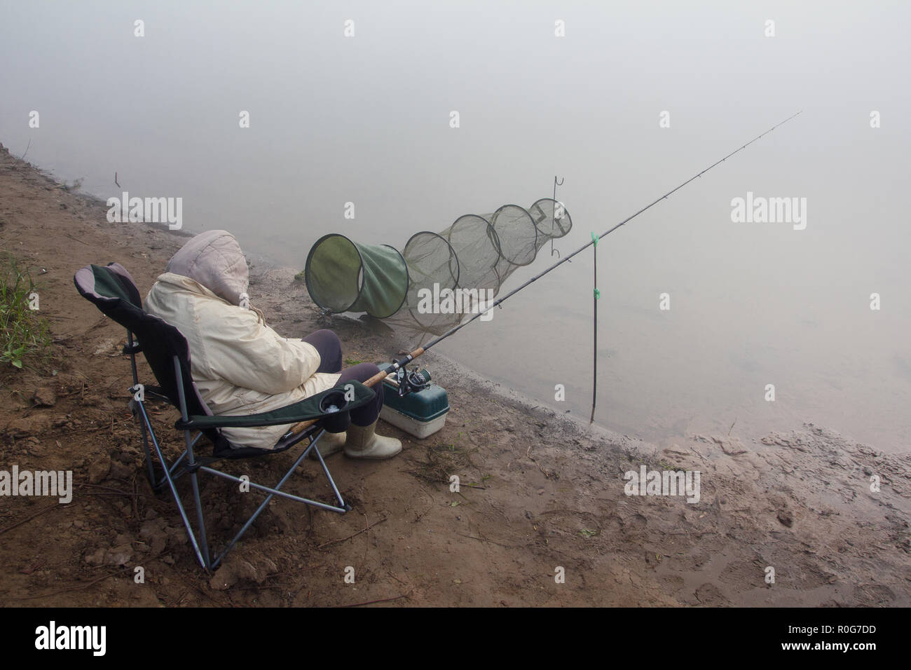 Morgen auf dem Fluss. Fischerin schläft in einem Klappstuhl Stockfoto