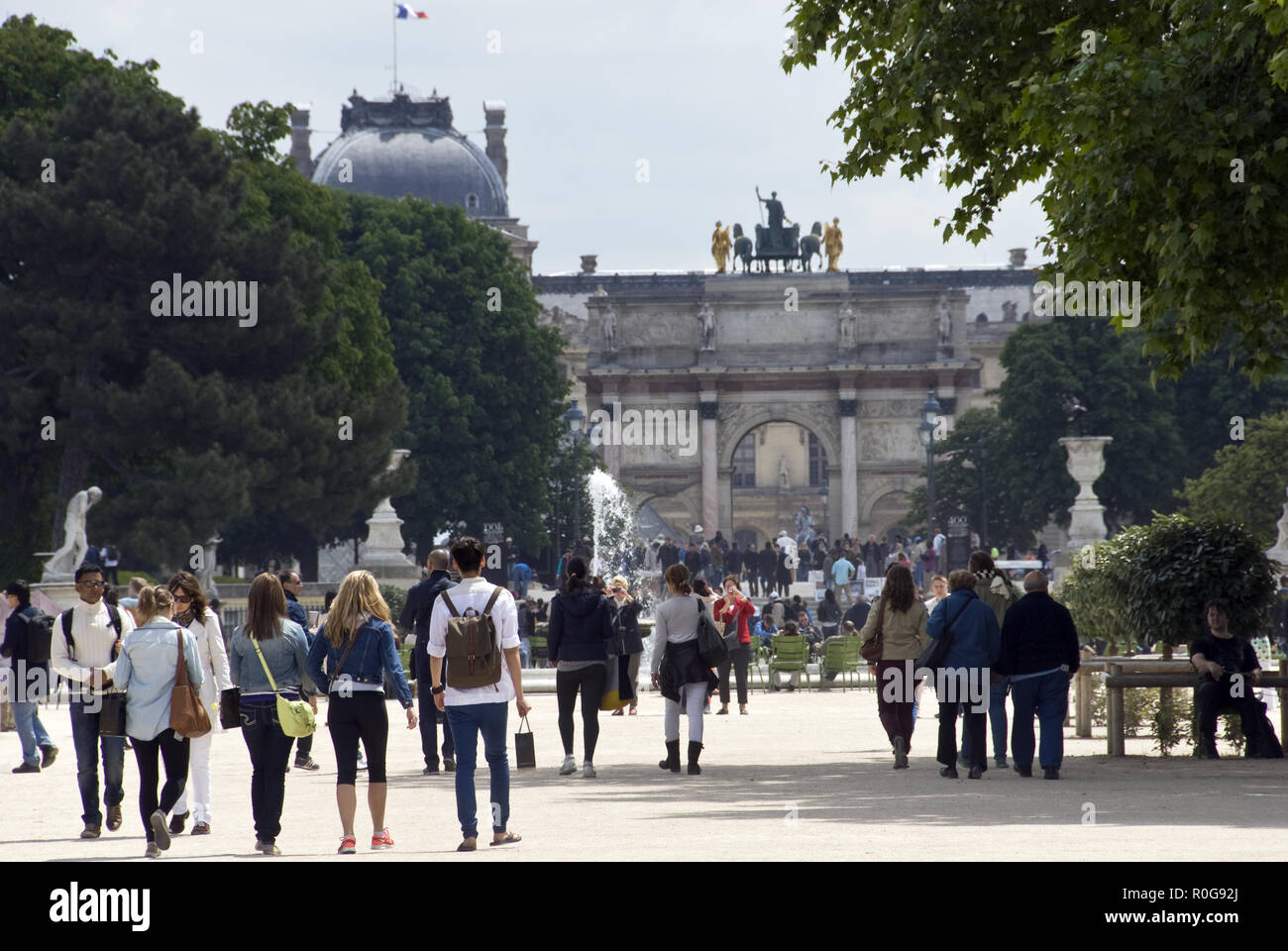 Menschen gehen durch den Jardin des Tuileries in Richtung Arc de Triomphe du Carrousel und dem Louvre, Paris, Frankreich. Stockfoto