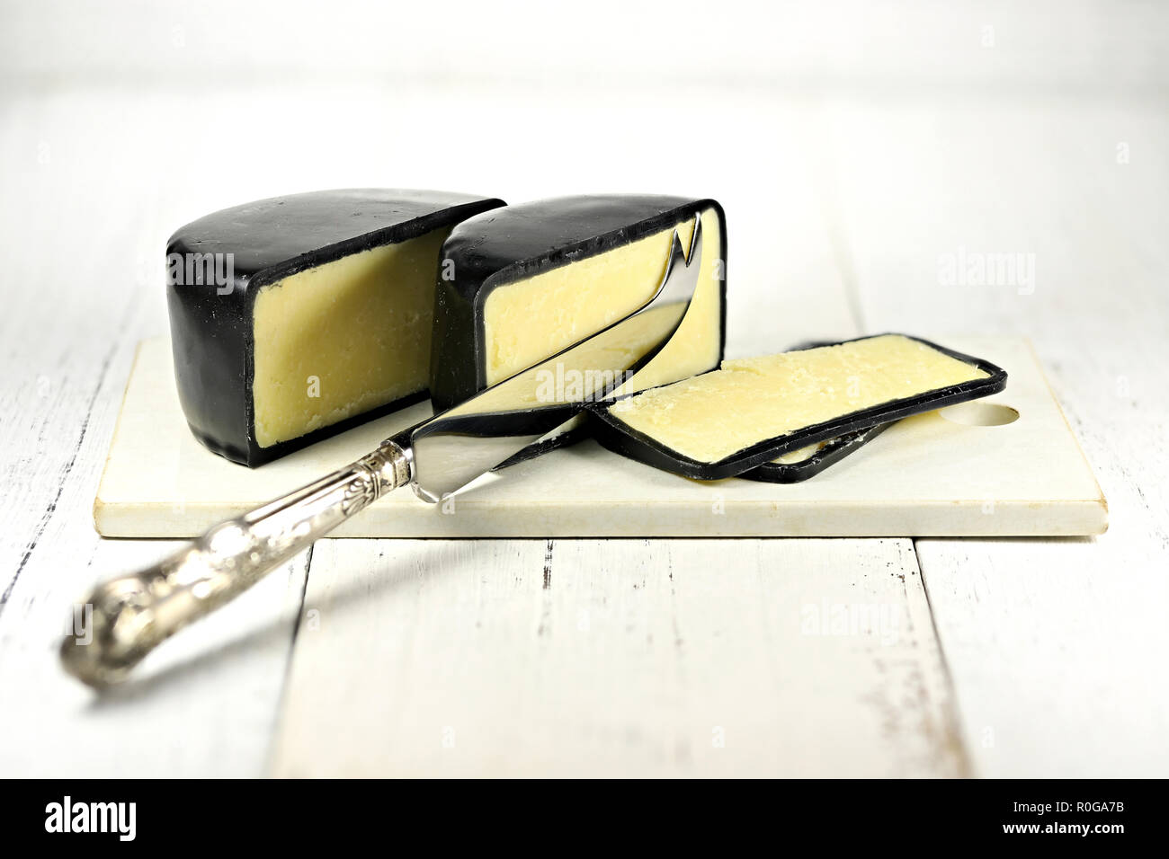 Reife Cheddar Käse mit silber Messer und Keramik Schneidbrett auf hölzernen Hintergrund isoliert Stockfoto