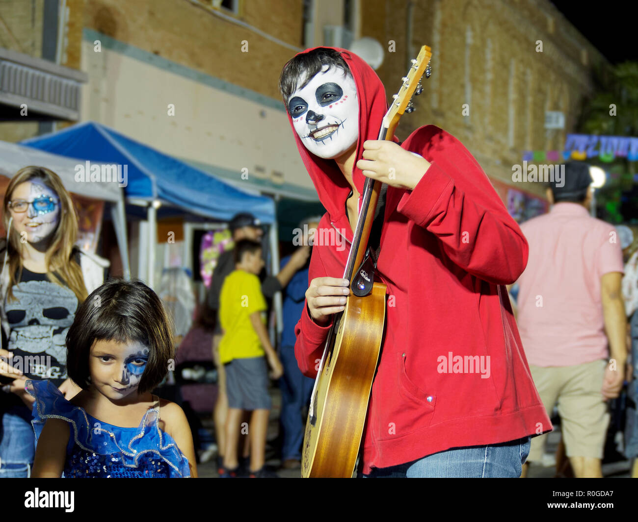 Ein Gitarrist in Gesicht Farbe und rot Kapuzenjacke am 2018 Dia de Los Muertos oder, Tag der Toten, Feier in Corpus Christi, Texas USA. Stockfoto