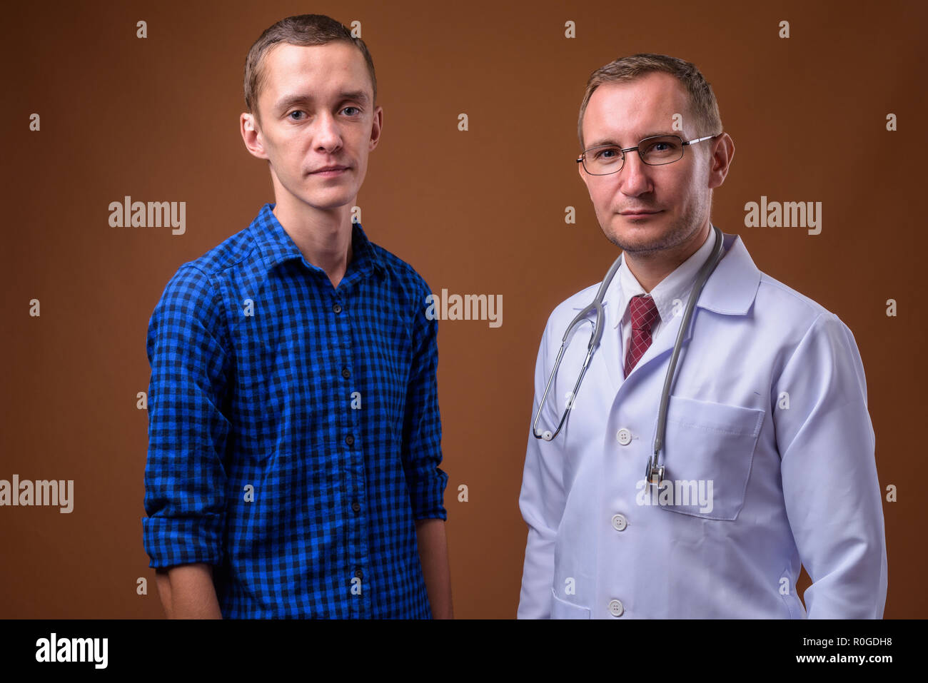 Mann Arzt und junger Mann Patienten gegen braunen Hintergrund Stockfoto