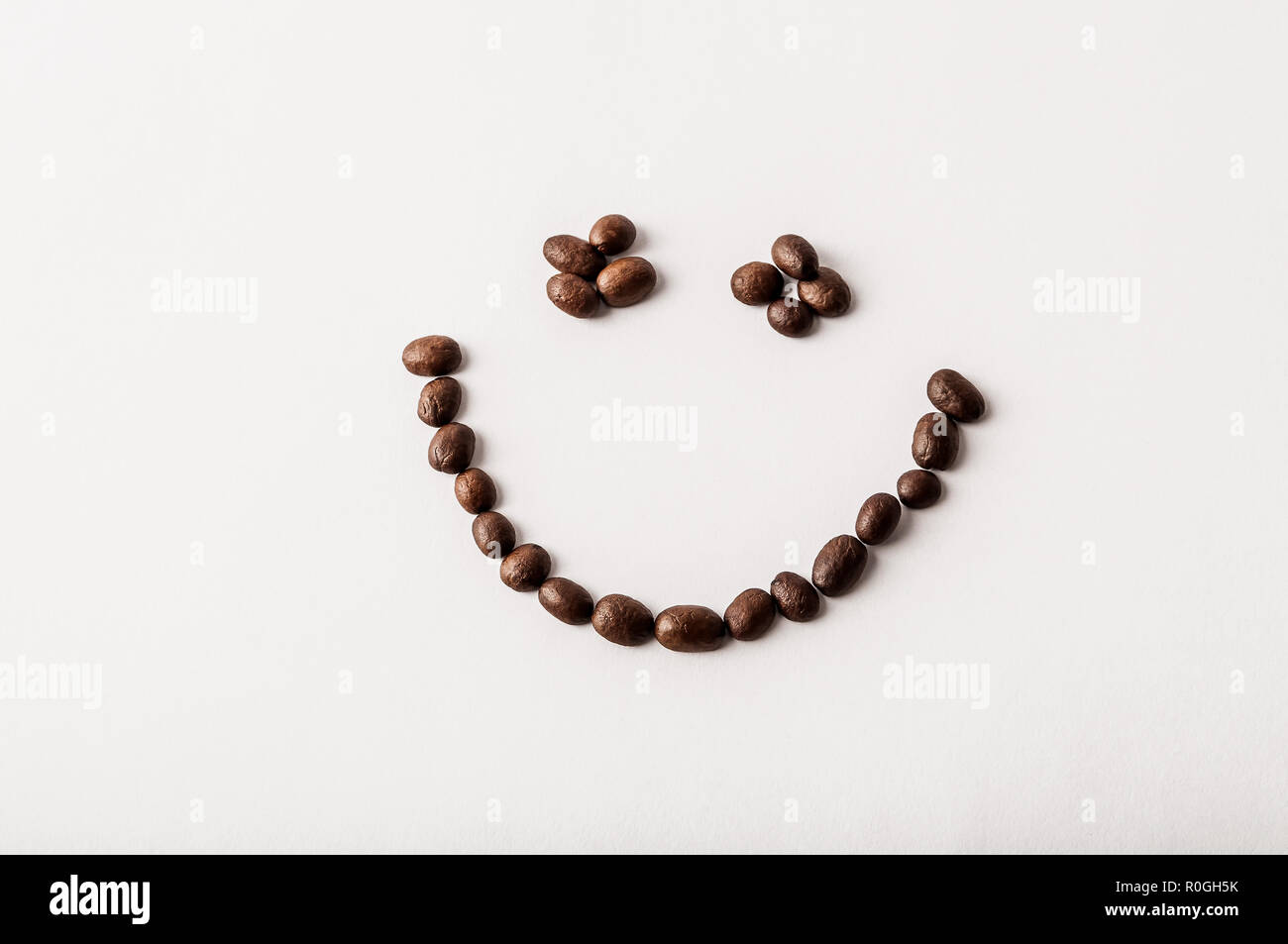 Fair trade Bio Kaffeebohnen geröstet angeordnet, wie ein Lächeln auf weißem Hintergrund - Begriff des Koffeins sucht, Frühstück, Energie oder Morgen happines Stockfoto