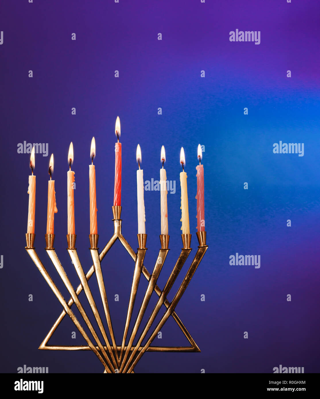 Die Leuchten von Hanukkah Kerzen in der Menorah auf blauem Hintergrund Stockfoto