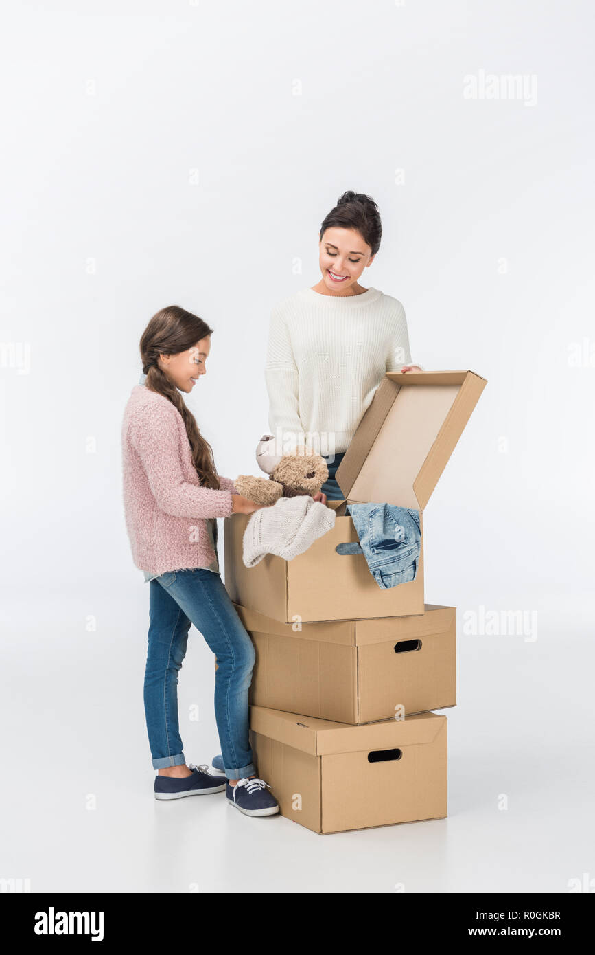Lächelnde Mutter und Tochter mit Kartons Umzug in neues Haus isoliert auf weißem Stockfoto