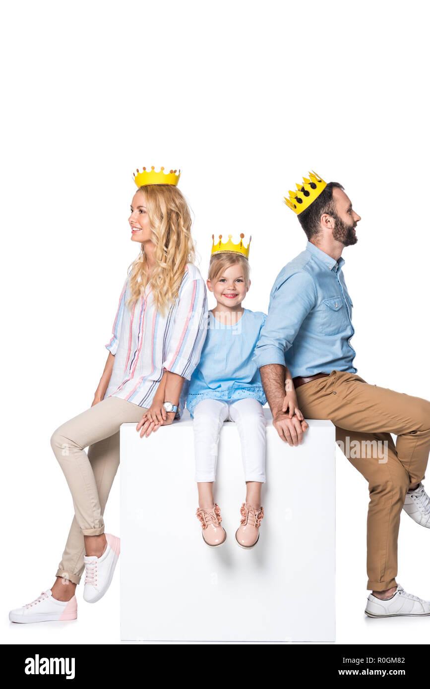 Familie mit gelben Karton Kronen sitzen auf White Cube isoliert auf weißem Stockfoto