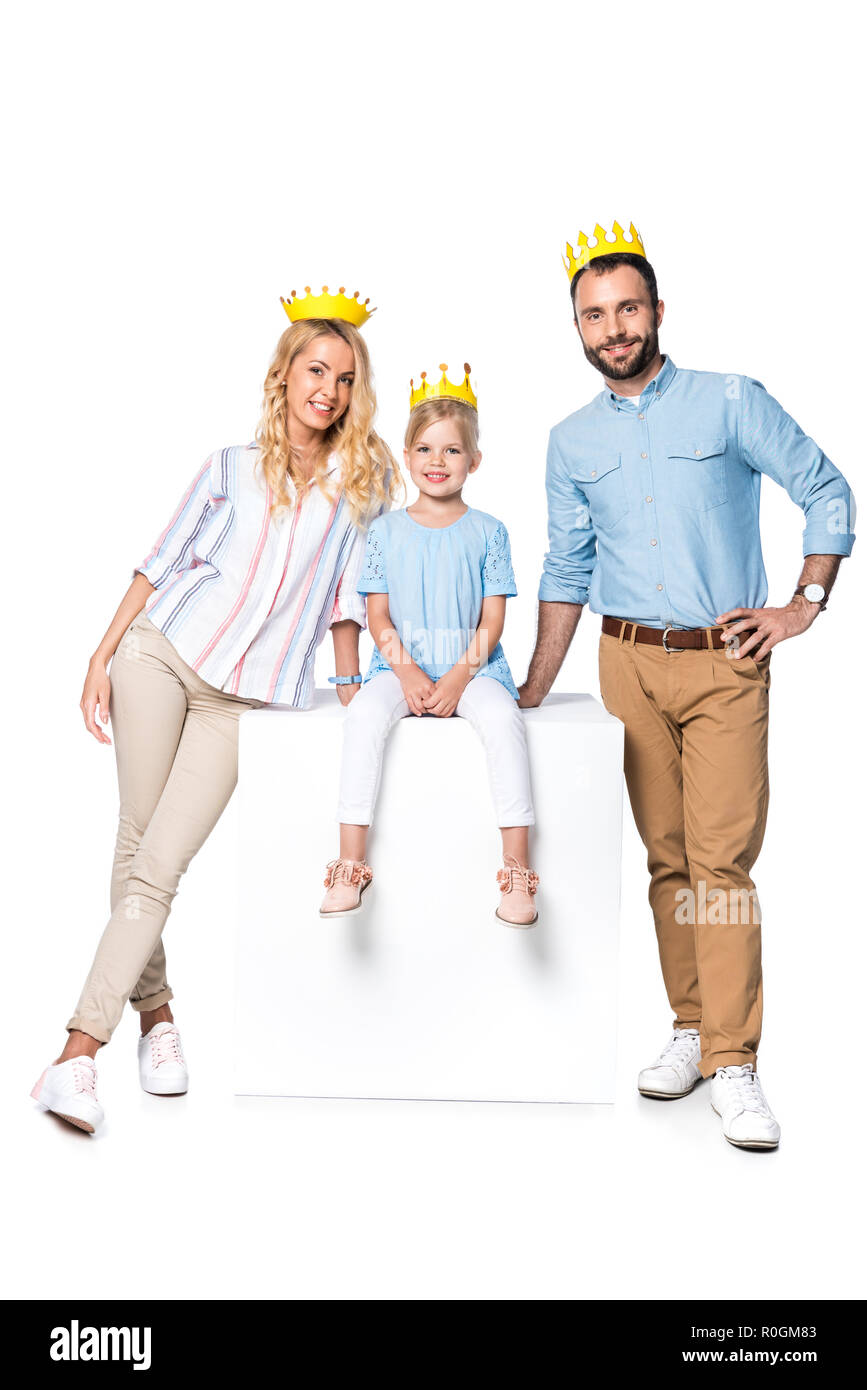 Glückliche Familie mit Karton Kronen sitzen auf White Cube isoliert auf weißem Stockfoto