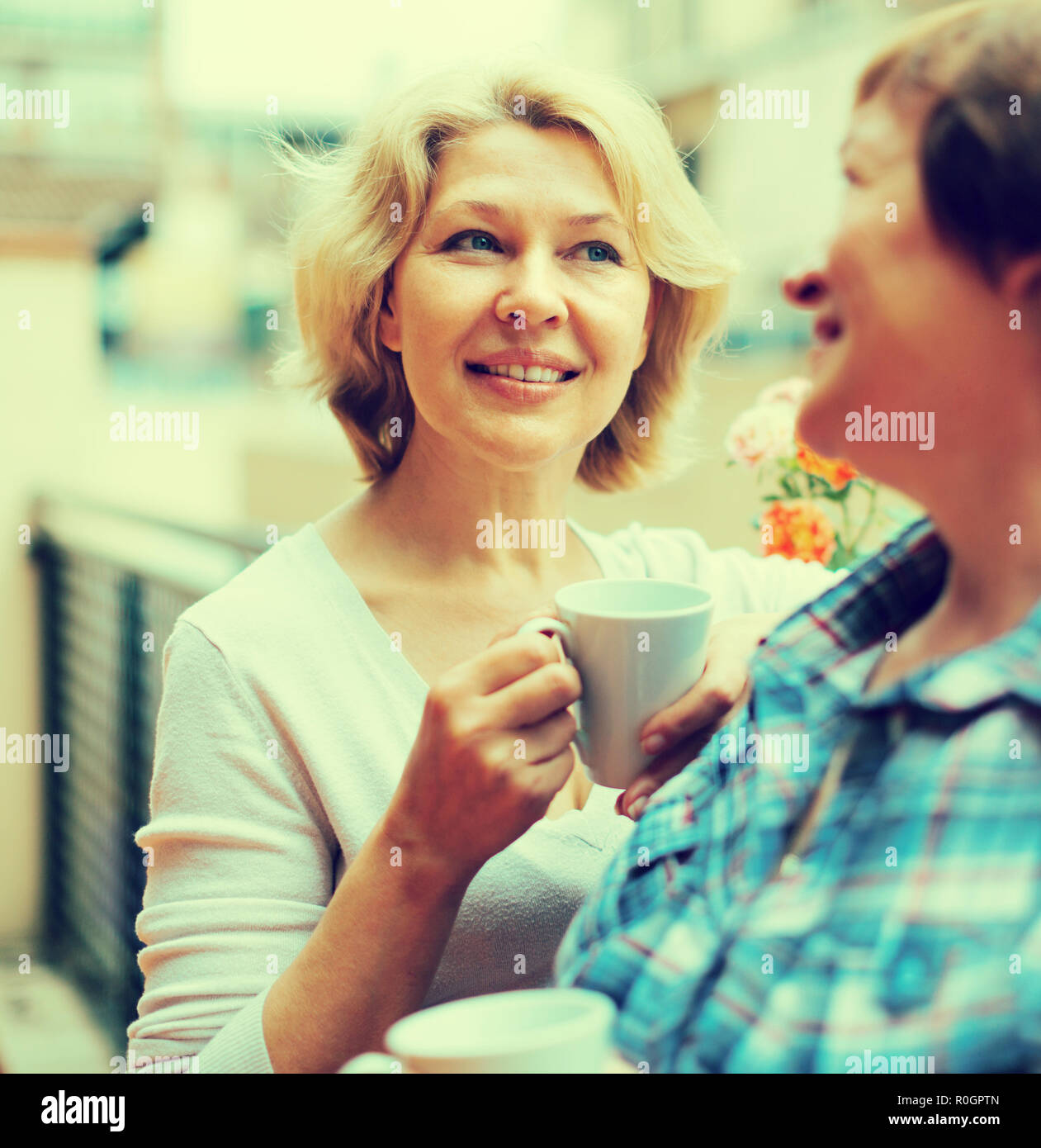 Lächelnd im Alter Freundinnen Aufenthalt auf Balkon mit Kaffee in Händen Stockfoto