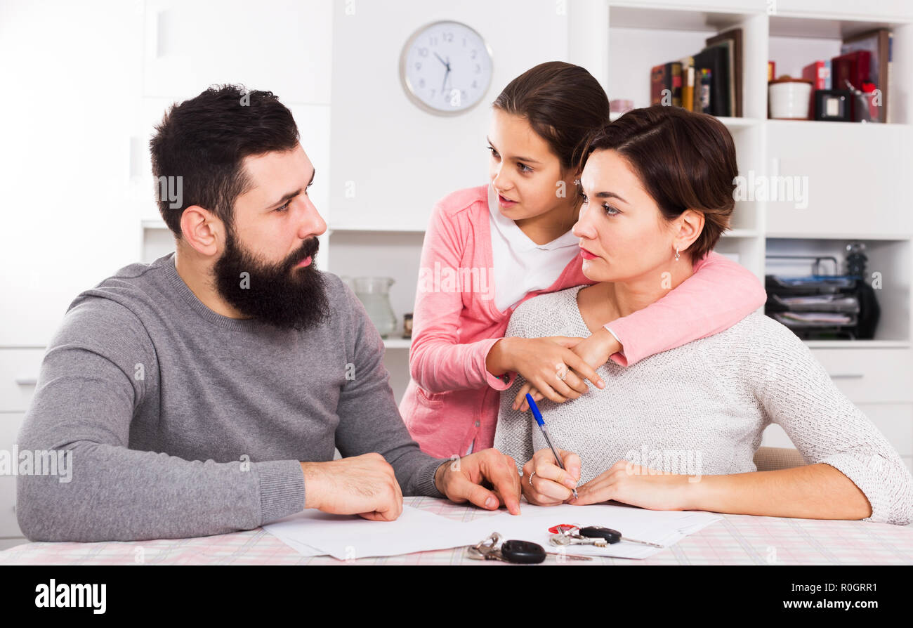 Junge Eltern Unterzeichnung Papiere für Scheidung, während ihre Tochter zu Hause Innenraum Stockfoto