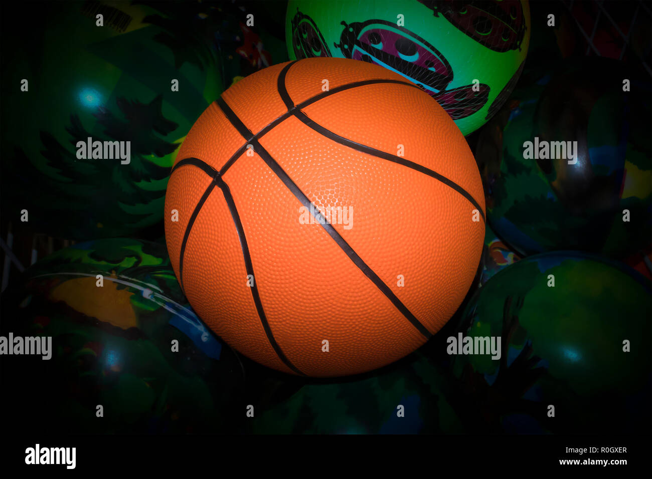 Helles orange Basketball Ball gegen grün lackiert Kugeln mit dunklen Vignette Stockfoto