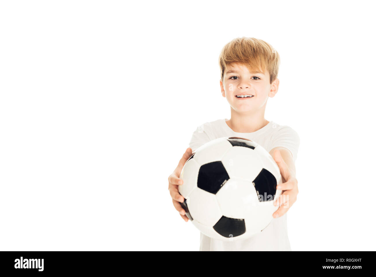 Lächelnd adorable Boy zeigt Fußball-Ball isoliert auf weißem Stockfoto