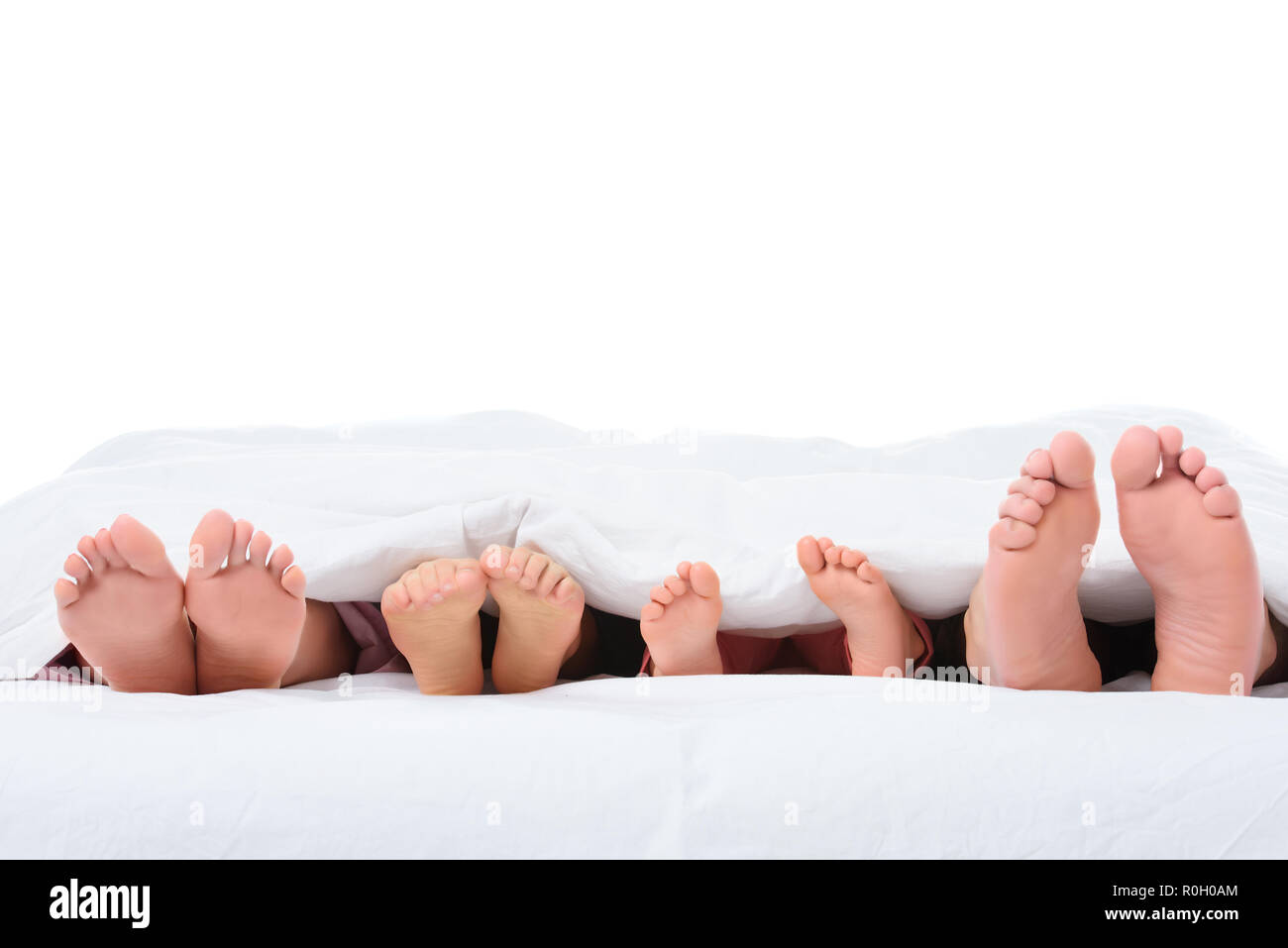 Familie Füße im Bett unter weißen Decke, isoliert auf weißem  Stockfotografie - Alamy