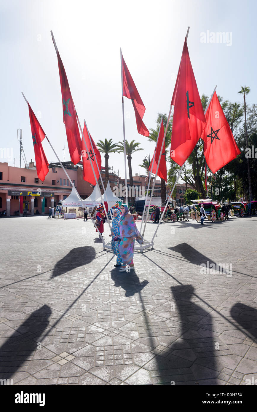 Zwei afrikanische Frauen in den Straßen von Marrakesch hetzen auf Platz Djemaa el-Fna durch Kreis der marokkanischen Flaggen umgeben Stockfoto