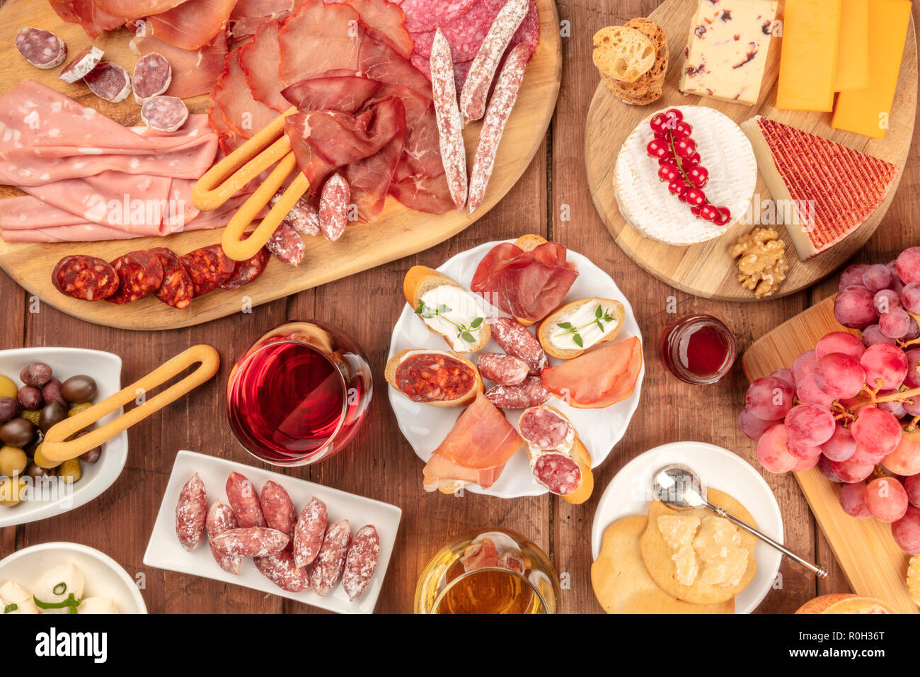 Charcuterie Verkostung. Ein Foto von vielen verschiedenen Wurst und Schinken, Aufschnitt, und eine Käseplatte, geschossen von oben auf einem urigen Hintergrund mit Rotwein Stockfoto