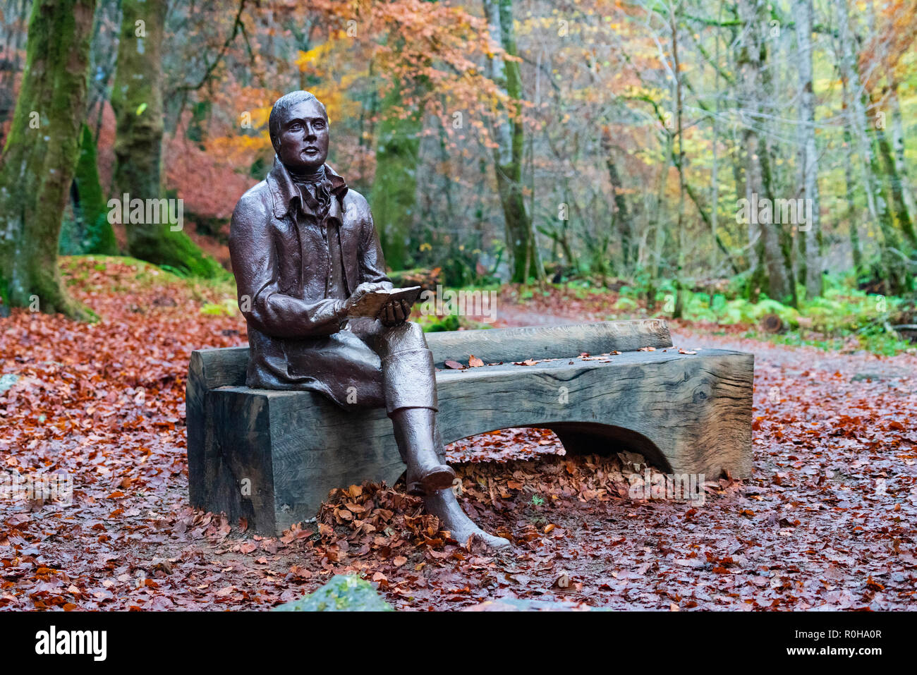 Statue des Dichters Robert Burns sitzt auf der Bank im Herbst am Birks O'Aberfeldy Scenic Area in Aberfeldy, Perthshire, Schottland, Großbritannien Stockfoto
