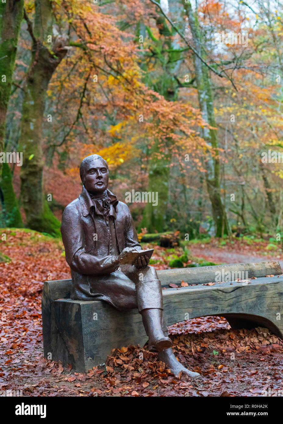 Statue des Dichters Robert Burns sitzt auf der Bank im Herbst am Birks O'Aberfeldy Scenic Area in Aberfeldy, Perthshire, Schottland, Großbritannien Stockfoto