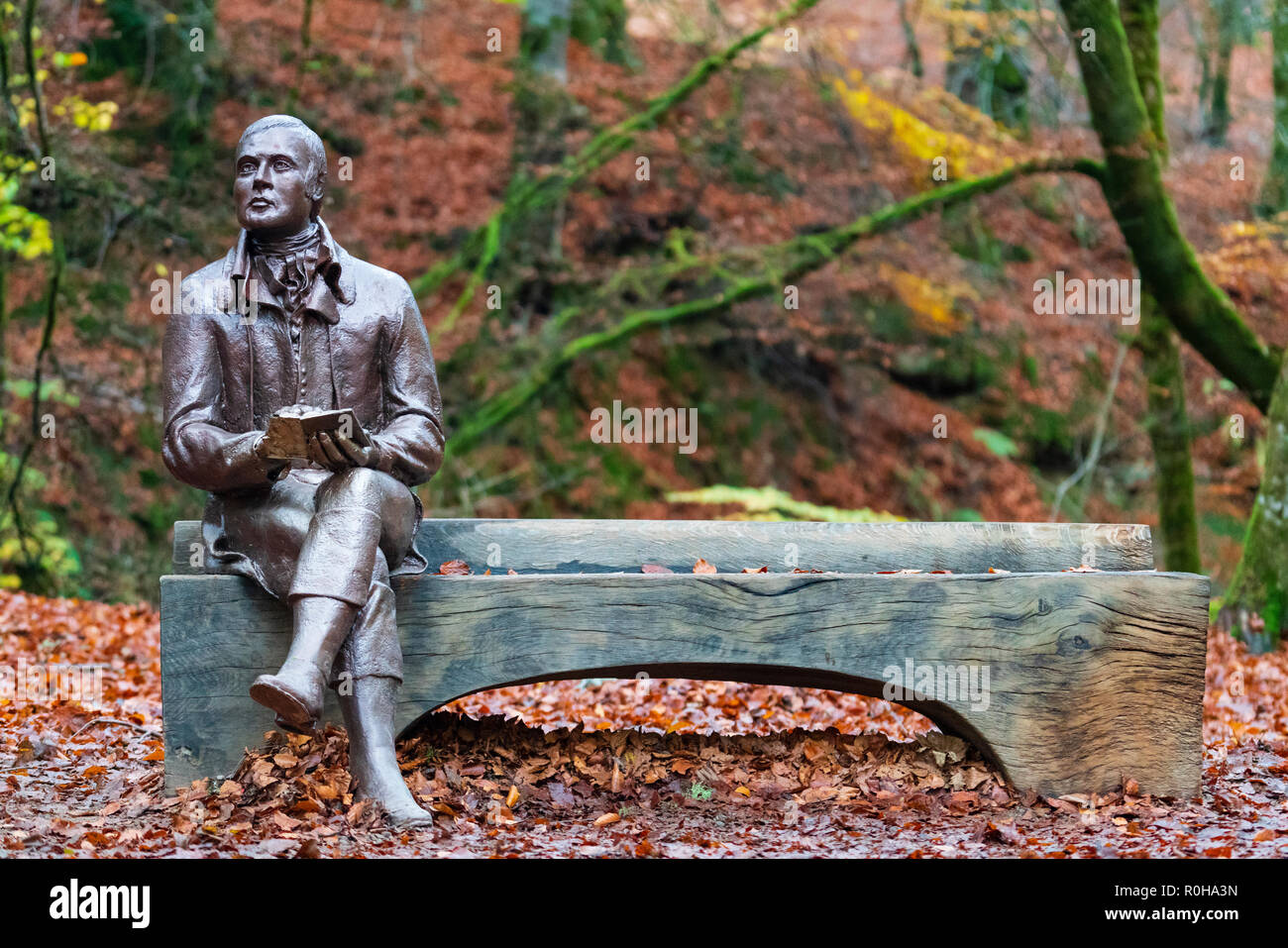 Statue des Dichters Robert Burns sitzt auf der Bank im Herbst am Birks O'Aberfeldy Scenic Area in Aberfeldy, Perthshire, Schottland, Großbritannien Stockfoto