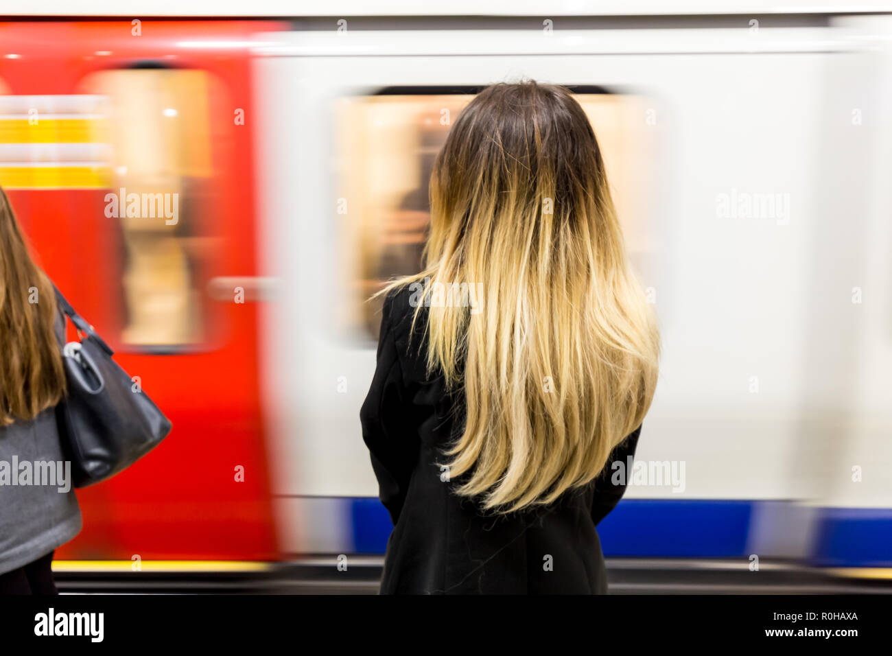 Junge Frau mit langen blonden Haaren wie Beschleunigung Rohr Zug kommt auf die Londoner U-Plattform Stockfoto