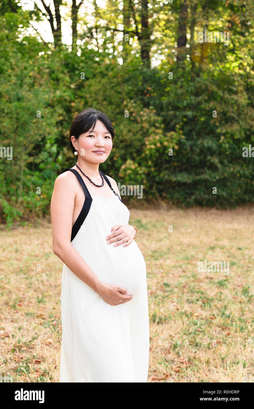 Schöne schwangere asiatische Frau im Park im warmen Sommertag Stockfoto