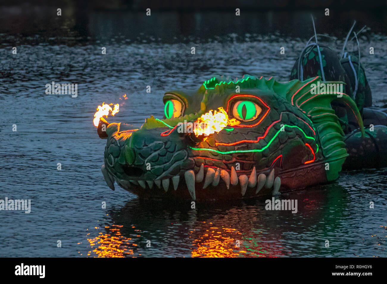 Grüner feuerspeiender Drache im Royal Albert Dock Liverpool, Großbritannien. November 2018. The Wave, River of Light Installation in der Bonfire Night 2018. Zehntausende von Menschen säumten sich auf beiden Seiten des Mersey für das kostenlose Spektakel, um Merseyside mit einem Feuerwerk und eigens in Auftrag gegebenen Lichtinstallationen zu sehen, darunter Straßenaufführungen am Ufer, darunter feueratmende schwimmende Drachen, Tier-, Kunst-, Fantasy-, isolierte, Flamme, Monster, bunt, Zeichnung, Kopf, Mythologie, aggressiv, heiß, Bewegung, Macht, Skala, exotisch, Haustier. Stockfoto