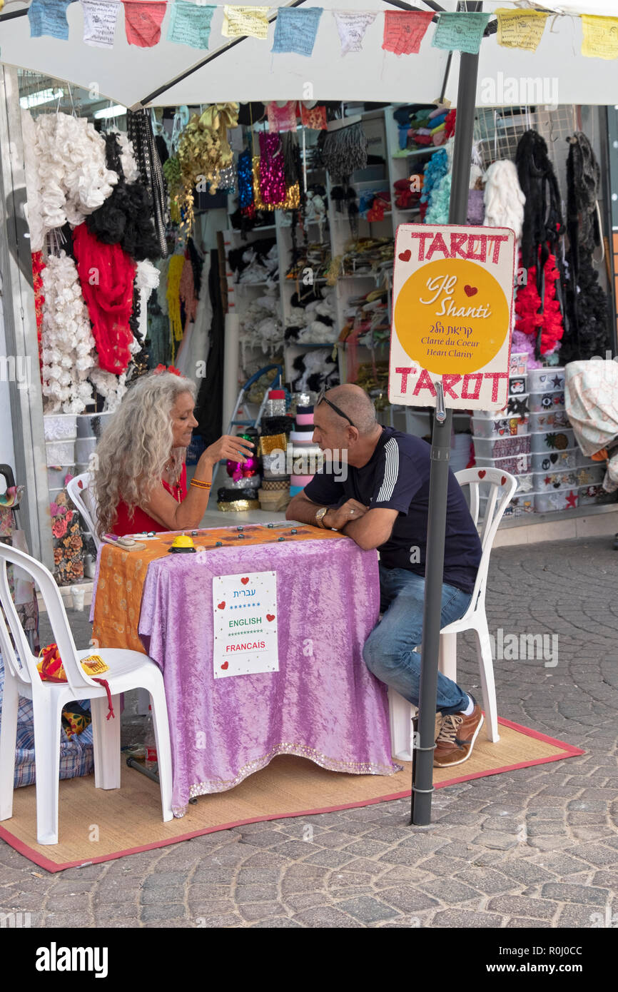 Ein tarot Card Reader und Ihrem Kunden am Carmel-markt in Tel Aviv, Israel. Ihr Zeichen ist in drei Sprachen. Stockfoto