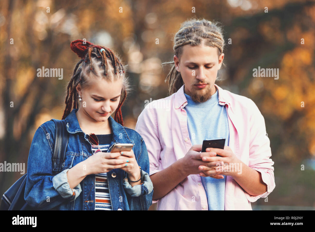Zwei hipster beste Freunde mit dreads legere Kleidung Nachrichten auf ihren Smartphones und nicht achten auf jedes andere, im Freien. Stockfoto