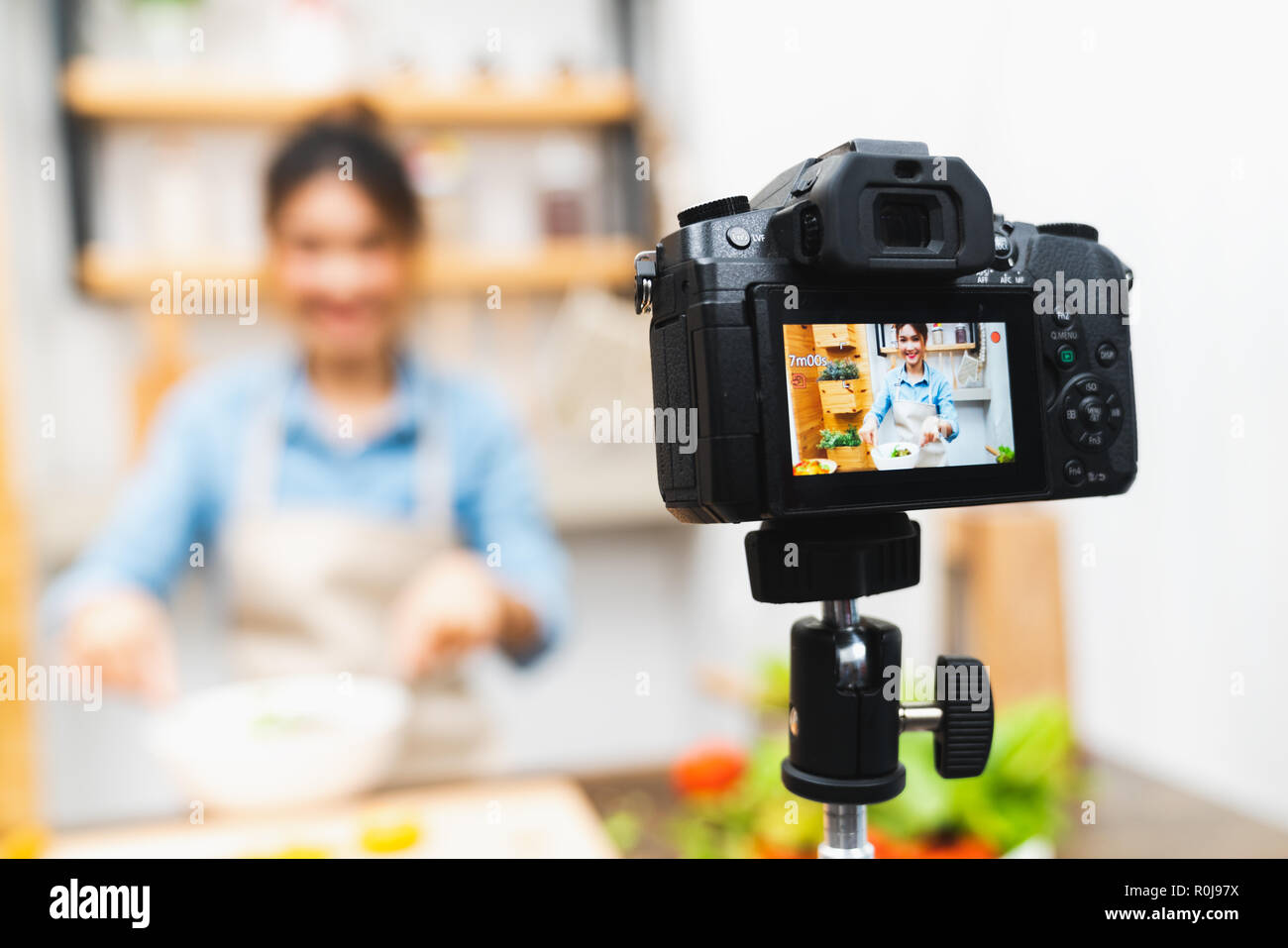 Junge süße Asiatische blogger Mädchen Aufnahme video tutorial Sitzung von Salat Kochkurs in der Küche zu Hause. Essen Bloggen oder vlogging, social media Hobby Stockfoto