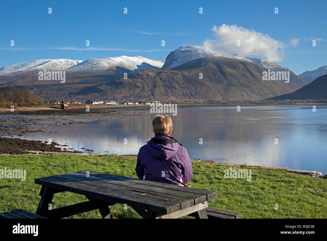 Einsame Frau sitzt mit Blick über den Loch Linnhe in Richtung, Ben Nevis, Lochaber, Schottland, Großbritannien Stockfoto