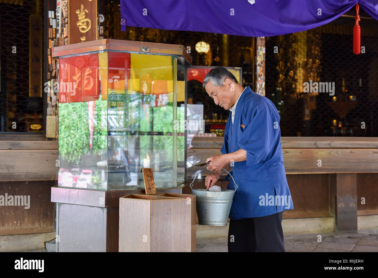 Ältere Arbeitnehmer entfernen brannten Kerzen Tempel in Kyoto. Stockfoto