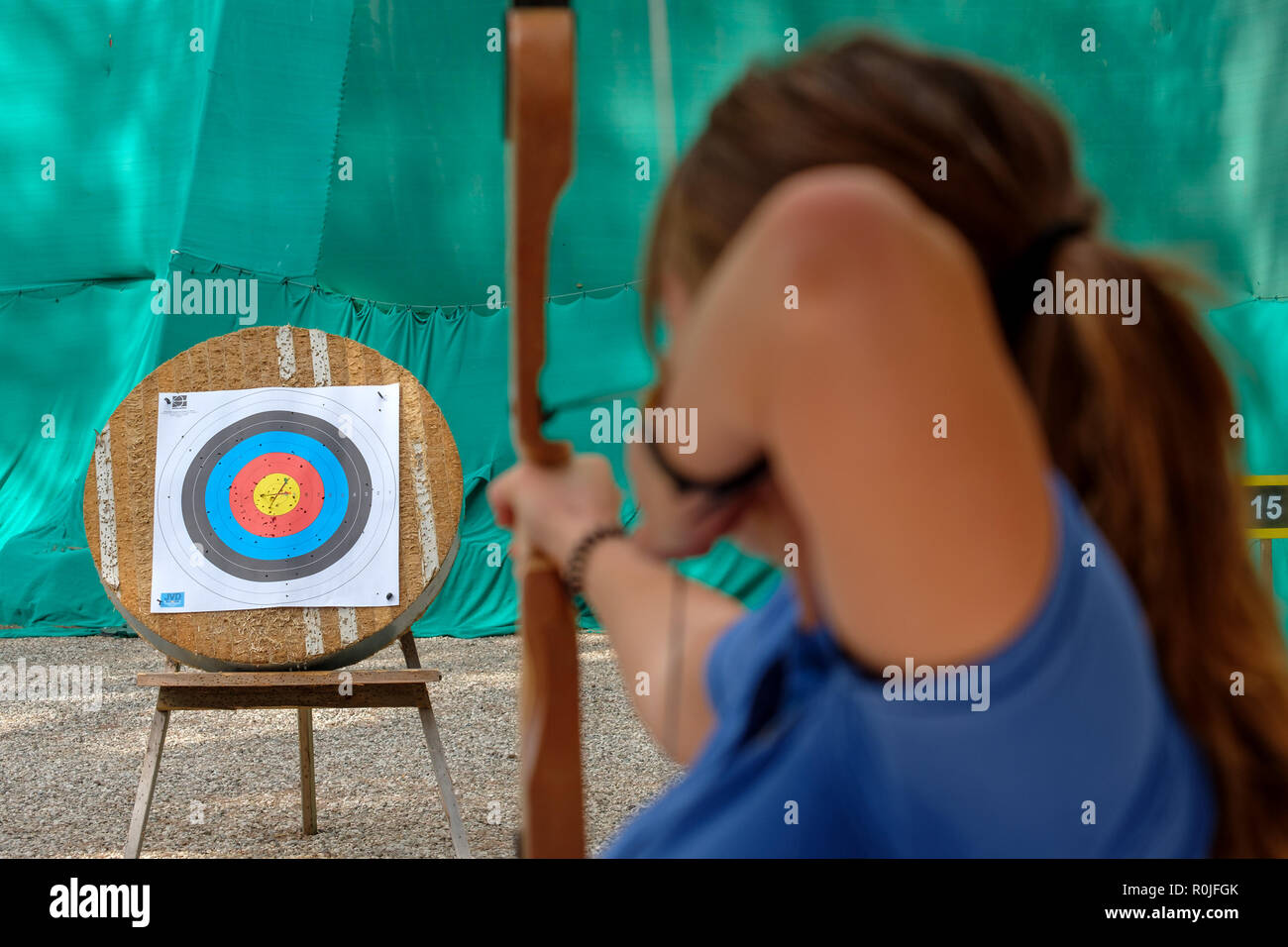 Rückansicht einer Frau schießt einen Pfeil mit Bogen zu einem Bogenschießen Ziel Stockfoto