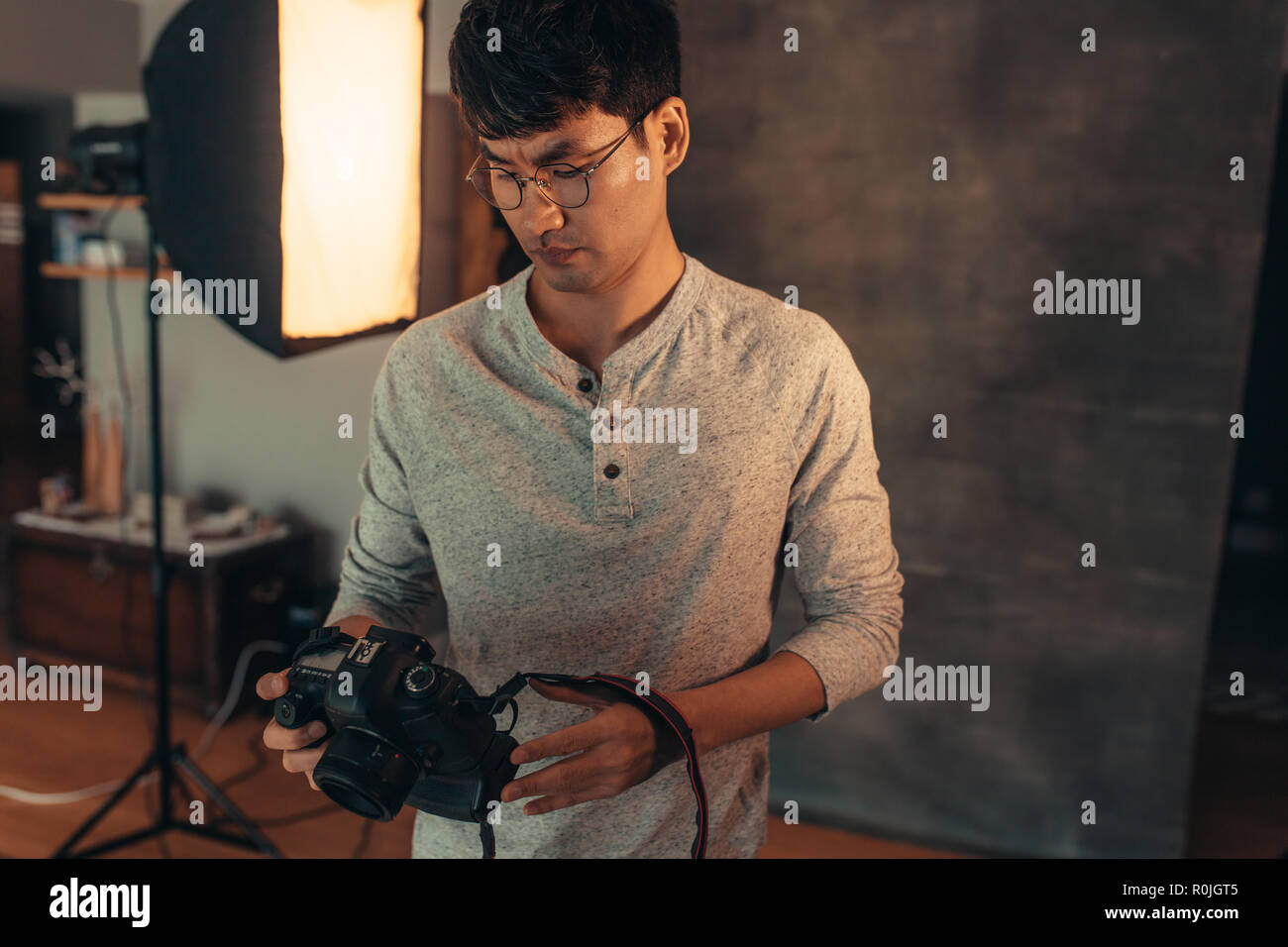 Asiatische männlichen Fotograf Kontrolle und Einstellung seiner DSLR-Kamera einstellung im Studio. Fotograf seine Kamera einrichten, bevor die Aufnahmen im Studio. Stockfoto