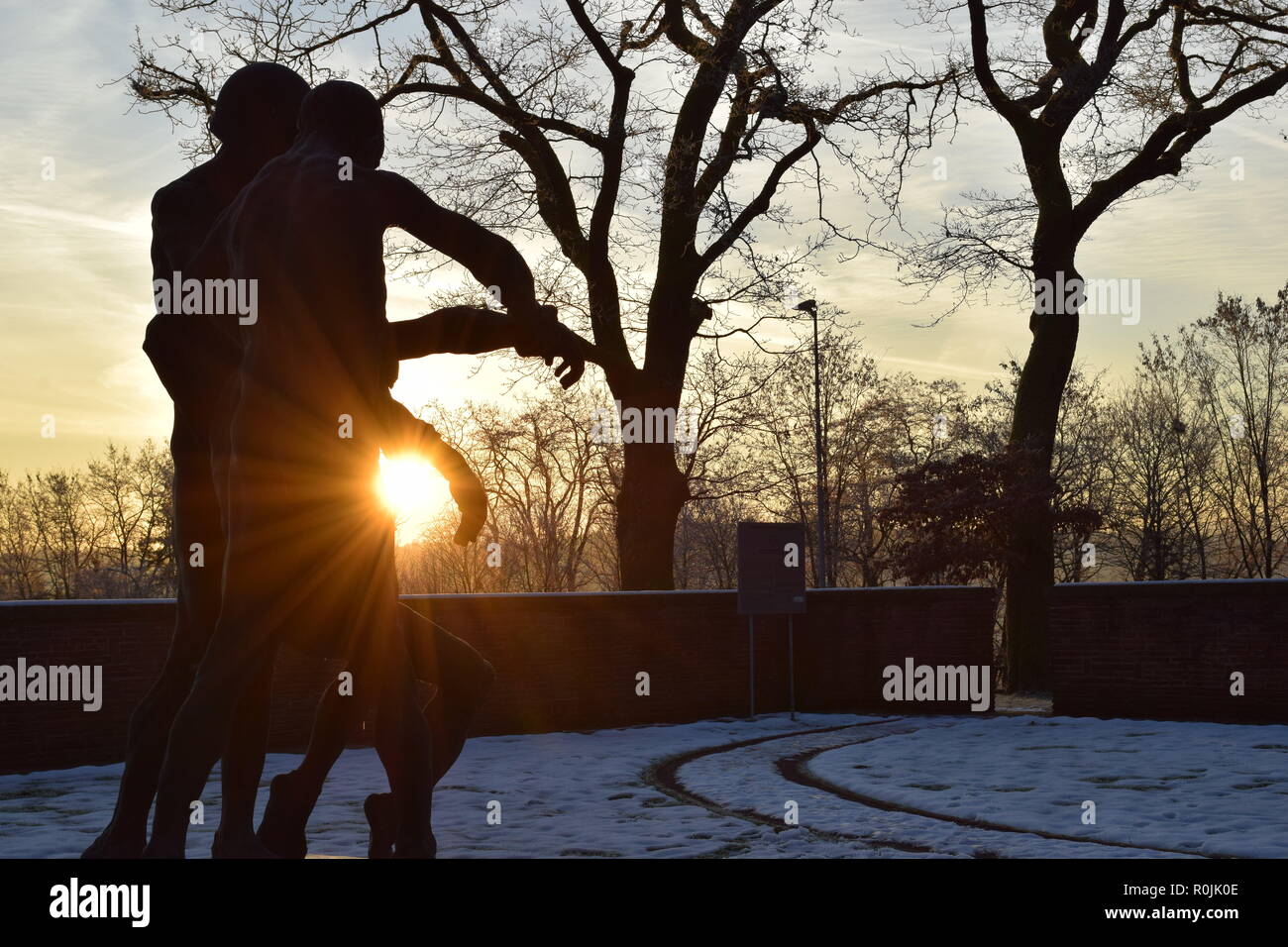 Timeline der aufgehenden Sonne im Winter Sonnenuntergang Himmel aus gesehen hinter dem Bronze Skulptur auf dem Soldatenfriedhof reimsbach an der Saar, Deutschland. Stockfoto