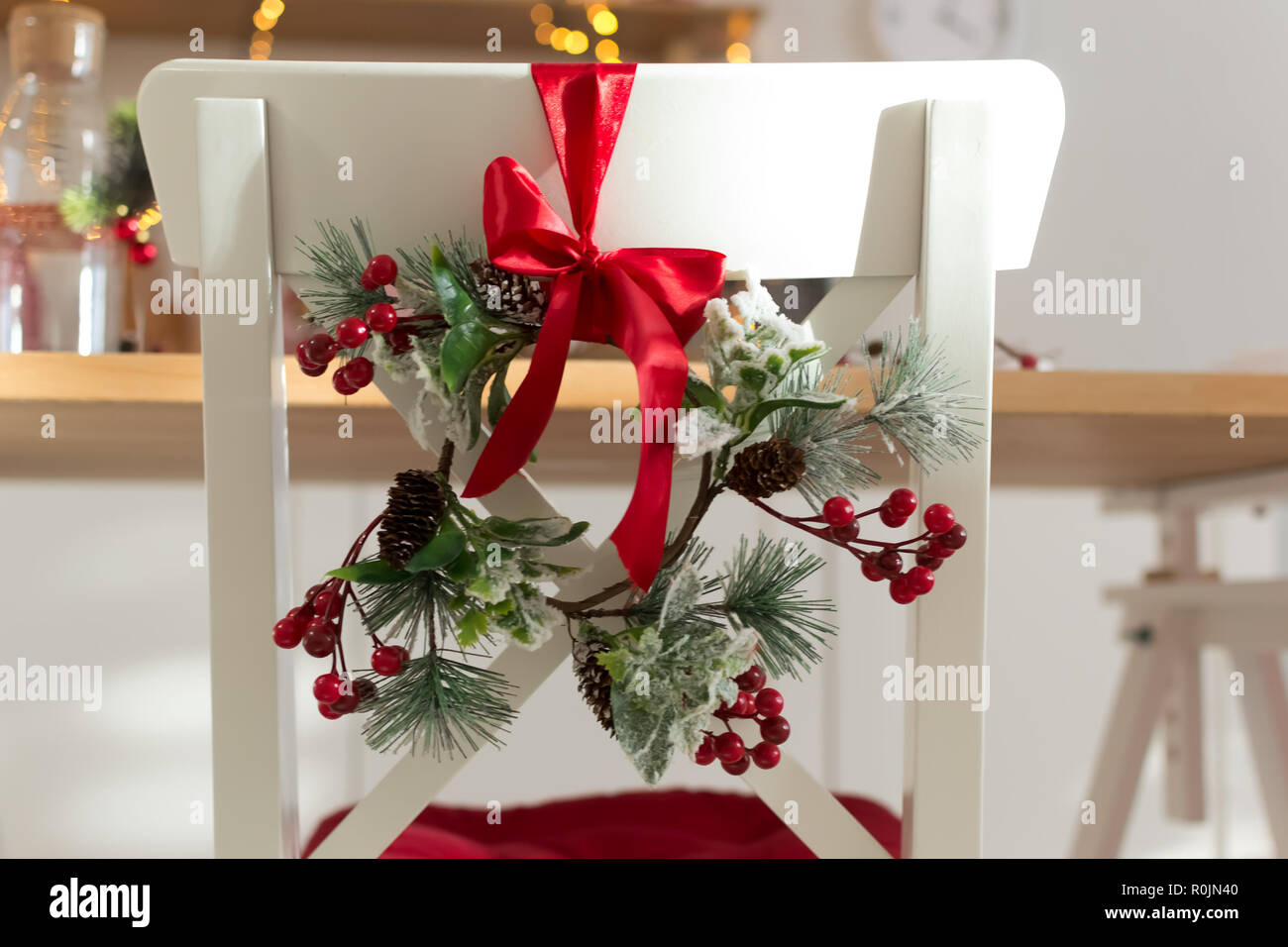 Gemütlich eingerichtet mit Weihnachtsschmuck mit roter Schleife und Tannenzweigen weiße Küche Stuhl Holz. Neues Jahr 2019 Stockfoto