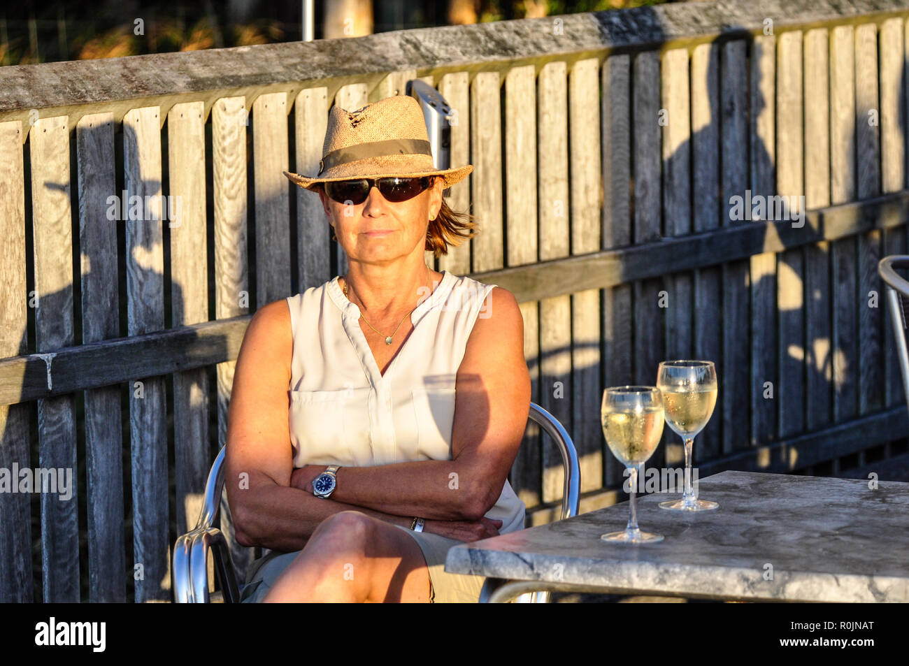 Brünette Frau mit Stroh Hut und Sonnenbrille genießt ein Glas Weißwein und der Küste Sonnenuntergang am Pier, Fraser Island, Australien. Stockfoto