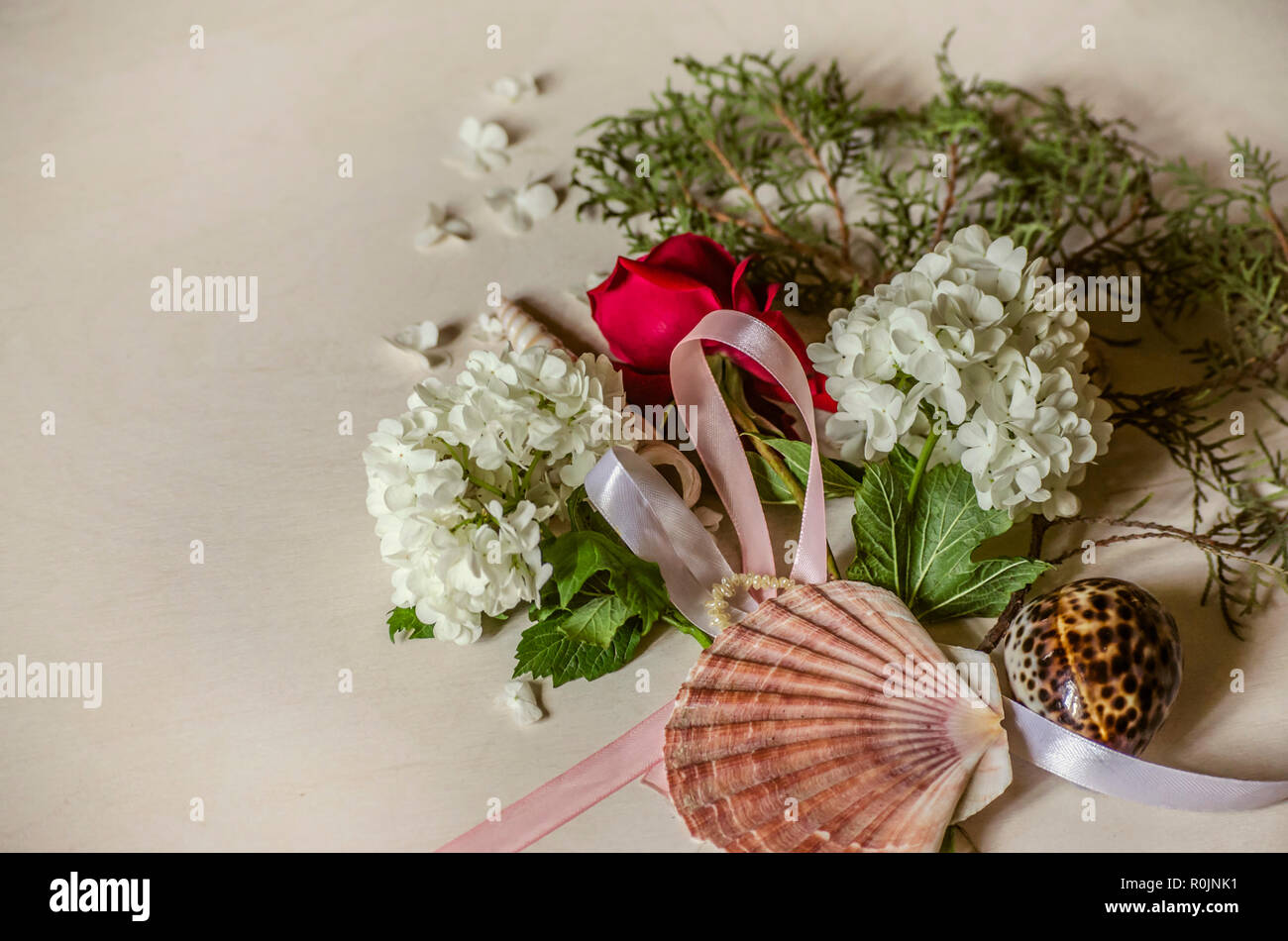 Zarter Bouquet weißer Hortensien mit einem Bud der roten Rose auf einem Zweig von Eukalyptus und Muscheln auf hellem Holztisch Stockfoto