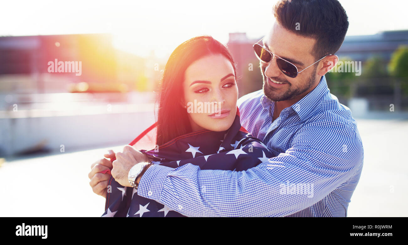 Junger Mann, die Frau, die mit USA-Flagge im Sonnenuntergang im Freien Stockfoto